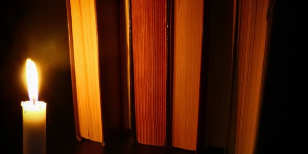 A candle lights up old books revealing the upcoming novel. Dark moon industries' snowbound novel.