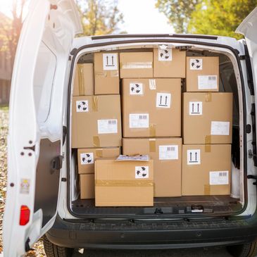 Van loaded with cardboard boxes ready for delivery on a sunny day.