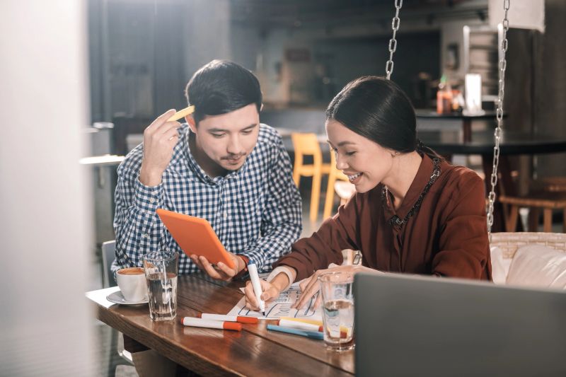 Helping girlfriend. Dark-haired handsome man wearing squared shirt helping girlfriend with project