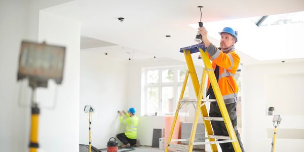 Een elektricien die aan het werken is en spotlichten instaleert.