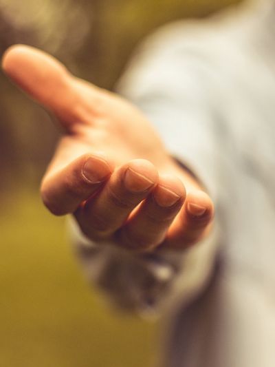 Person extending a hand forward in a gesture of offering or help.