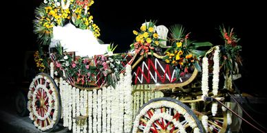 A beautifully decorated horse carriage adorned with vibrant flowers and garlands at night.