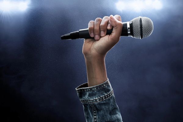 Hand holding a microphone on stage.