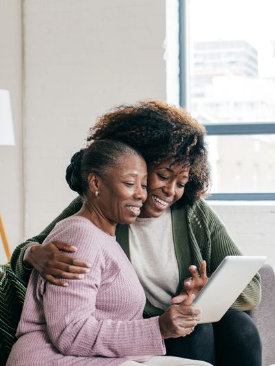 An adult woman helping her mother with a device.