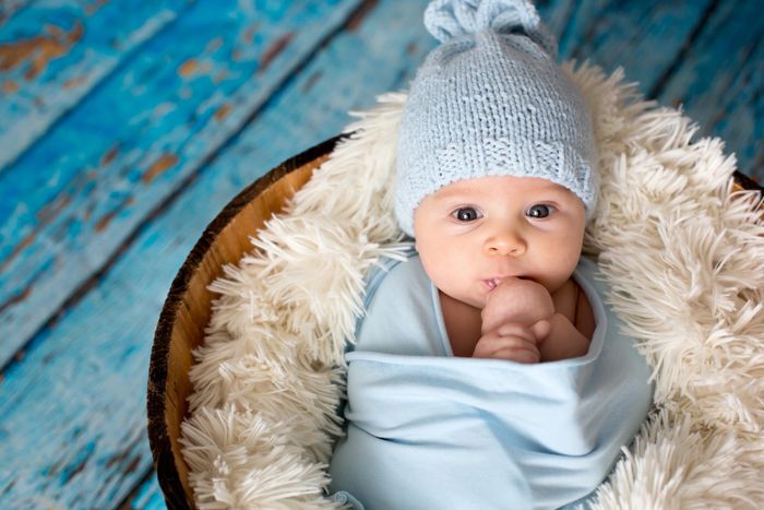 Adorable baby in a blue knit hat wrapped in a soft blue blanket.