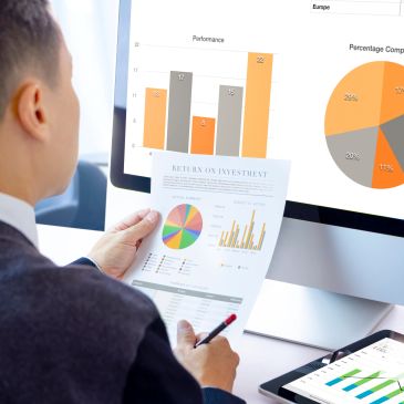 Business owner analyzing charts on computer and paper