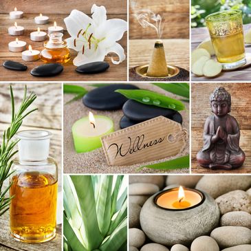 Wellness items including candles, oils, stones, and a Buddha statue arranged on wood and sand.