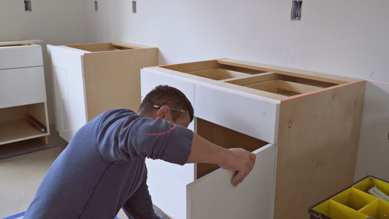 worker installing kitchen cupboard Installation of kitchen. Worker installs kitchen cabinet.