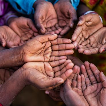 Multiple hands extended together, palms up, symbolizing unity and support.