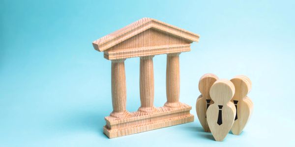 Wooden figures representing a courthouse and business people on blue background.