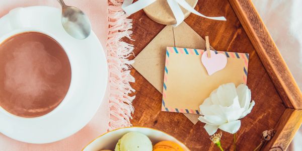 Breakfast tray with coffee, macarons, and a love note with a white rose.