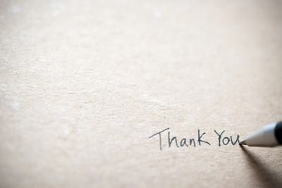 A pen writing 'Thank You' on textured paper.
