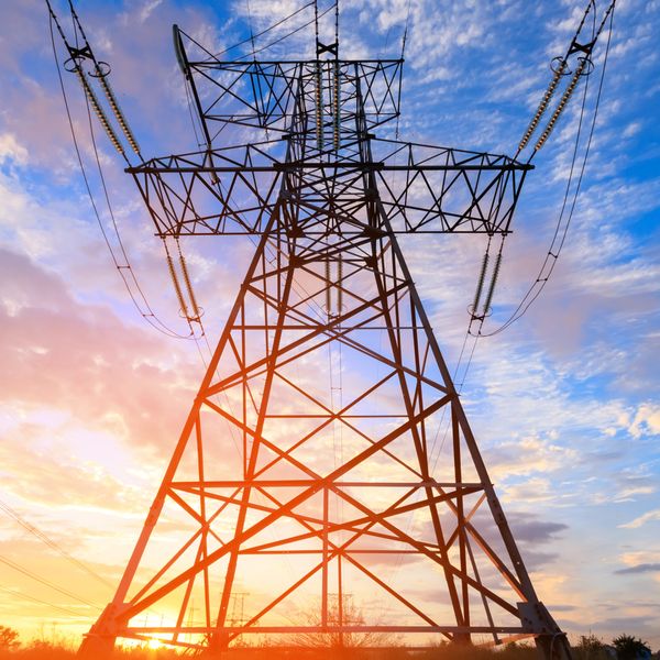 Electric power transmission tower against a colorful sunset sky.