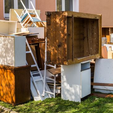 Pile of discarded old furniture outside a building.