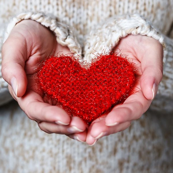 Hands holding a red fuzzy heart.