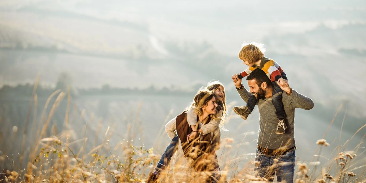 A happy family enjoying a sunny day outdoors in a field.