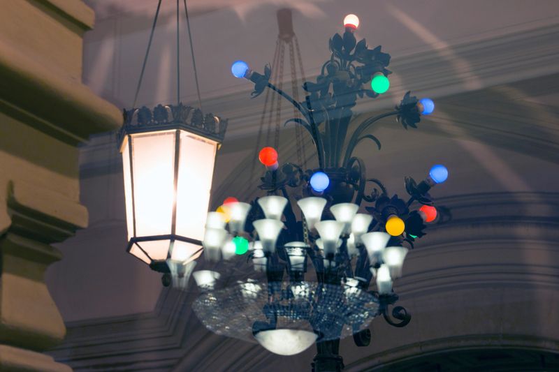 Reflections of various lamps (lantern, classical luster, multi-colored chandelier) in glass against the background of a classic interior. Selective focus