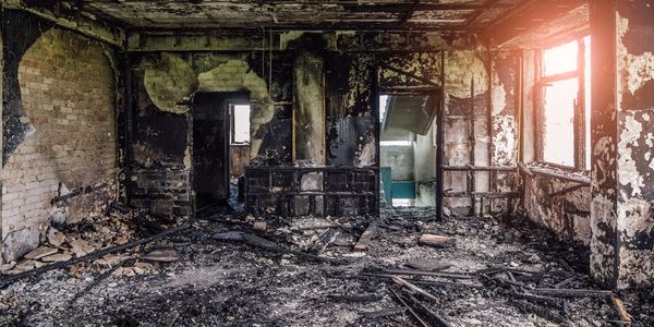 “Fire-damaged home interior with charred walls, smoke damage, mitigation by Top Notch Restoration.