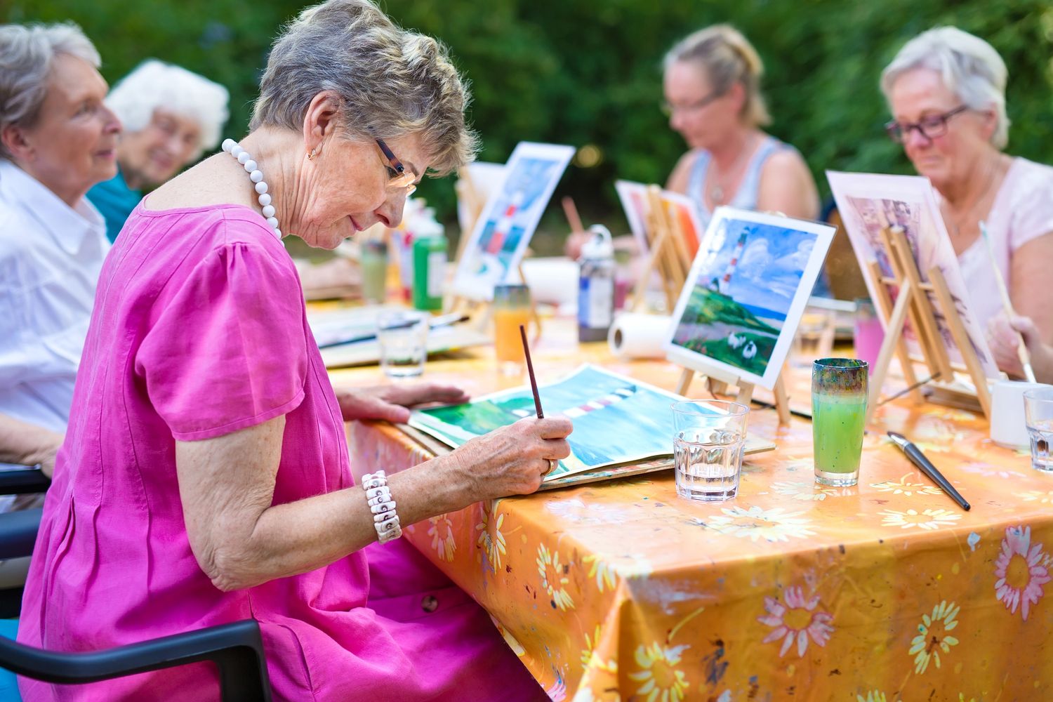 Seniors sitting and painting in an art class