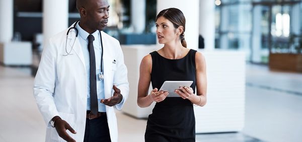 Three smiling healthcare workers in colorful scrubs posing together.