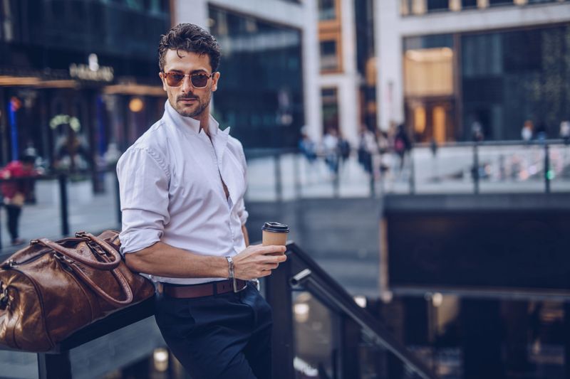 One young handsome businessman drinking takeaway coffee on the street