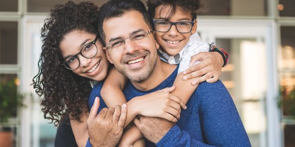 Happy family with glasses sharing a warm embrace and smiles indoors.