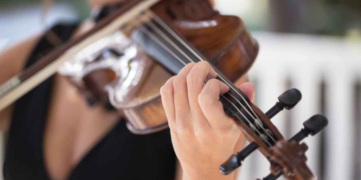 Close-up of hand playing violin strings.