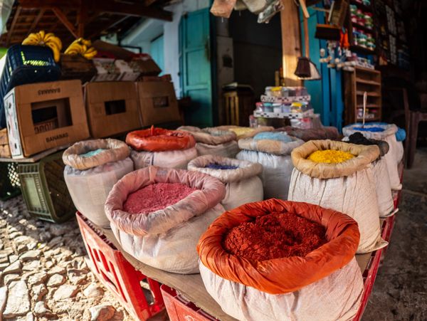 Colorful powdered spices in sacks displayed at an outdoor market stall.