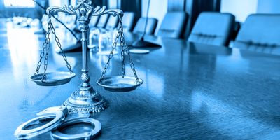 Scales of justice and handcuffs on a conference table in a legal setting.