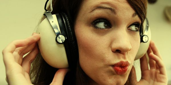 Young woman wearing large vintage headphones, making a playful expression.