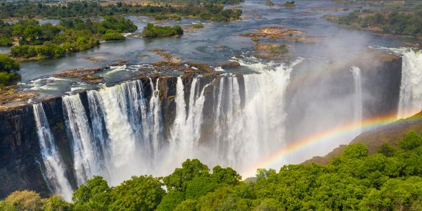 Victoria Falls with a vibrant rainbow over the cascading water.