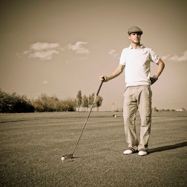 Man standing on a golf course holding a golf club, ready to play.
