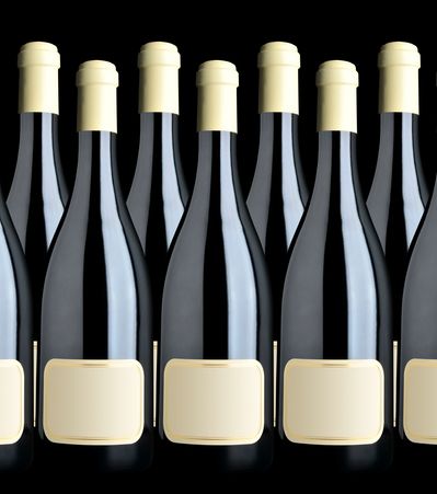 Rows of sleek black wine bottles with blank cream labels and caps.