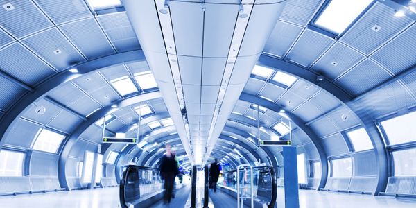 Futuristic airport terminal with people and moving walkways.