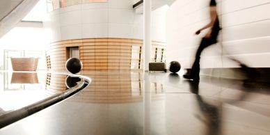 Modern interior with reflective floor and blurred figure walking.