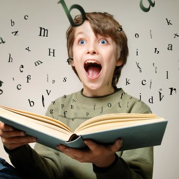 Excited boy reading a book with letters flying out.