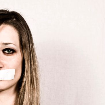 Woman with tape over her mouth, symbolizing silence or censorship.
