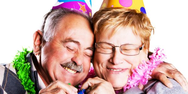 Happy elderly couple celebrating with party hats and decorations.