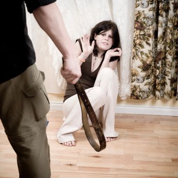 Woman scared of man with belt.