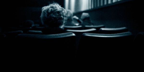 Person sitting alone in a dark theater.