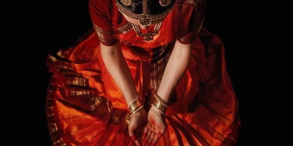 Person in traditional red attire with hands extended downward.