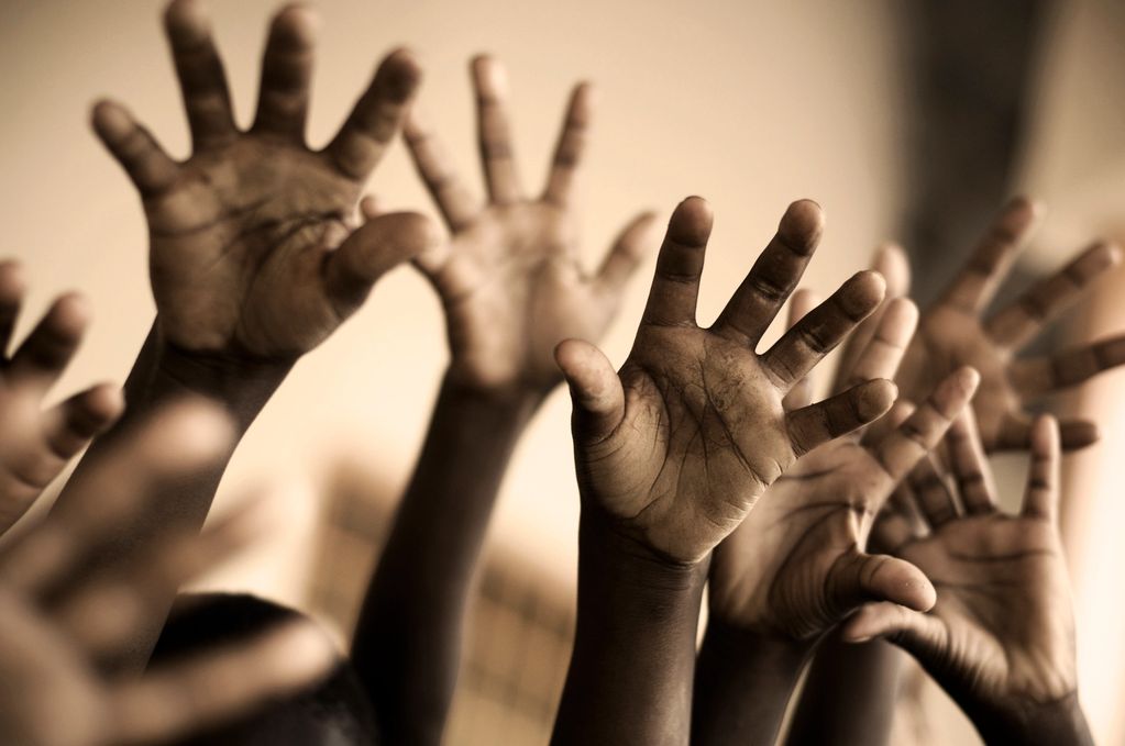 Several raised hands reaching upward.
