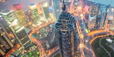 Aerial night view of a city with illuminated skyscrapers and busy roads.