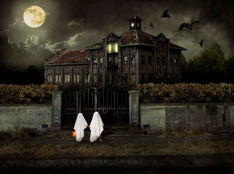 Two kids dressed up in ghost costumes go trick or treat at haunted house for Halloween. CLICK FOR SIMILAR IMAGES OR LIGHTBOX WITH SEASONAL IMAGES.
