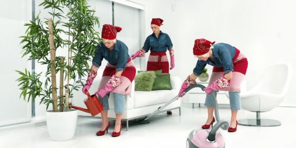 Three identical women cleaning a bright living room.