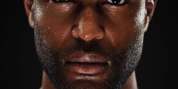 Close-up portrait of a serious man with a beard against a dark background.