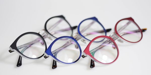Three pairs of eyeglasses in black, blue, and red frames.