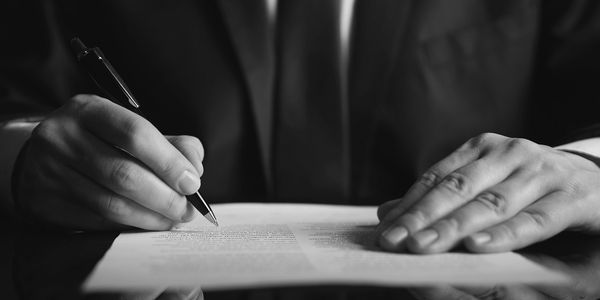 Person signing a document with a pen.