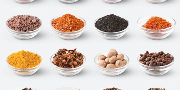 Various spices displayed in glass bowls in neat rows.