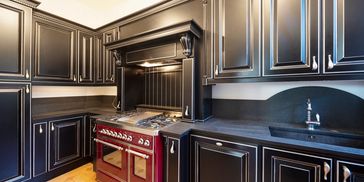 Elegant kitchen with black cabinets and a red stove.